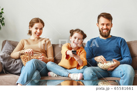 Happy family resting with snacks on couch at home. Happy family resting with snacks on couch at home. 65581661