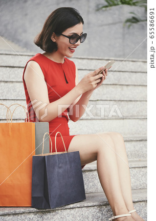 Happy shopaholic texting friends 65586691