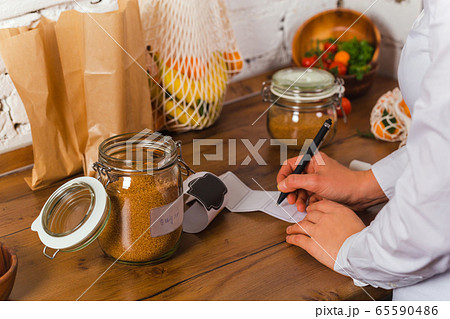 woman hand is writing name of product to stick on glass jar conscious shopping no plastic 65590486
