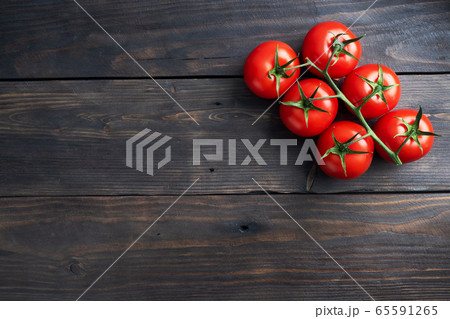 Cherry tomatoes on a branch. Fresh juicy red tomatoes on a dark wooden background. Copy space. Cherry tomatoes on a branch. Fresh juicy red tomatoes on a dark wooden background. Copy space. 65591265