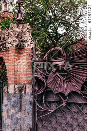 Red brick ornate vintage wall and iron dragon gate of Pavilion Guell in Barcelona Red brick ornate vintage wall and iron dragon gate of Pavilion Guell in Barcelona 65592124