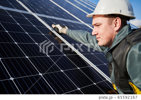 Workman standing on the ground trying to fasten solar batteries together, installing process Workman standing on the ground trying to fasten solar batteries together, installing process 65592167