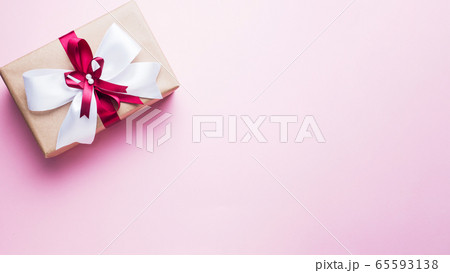 Gift or present box with a big bow on a pink table top view. Flatlay composition for Christmas birthday, mother day or wedding. Gift or present box with a big bow on a pink table top view. Flatlay composition for Christmas birthday, mother day or wedding. 65593138