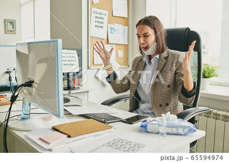 Irritated woman screaming in office Irritated woman screaming in office 65594974