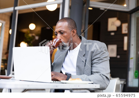 African American man working on his laptop at coffee terrace 65594975