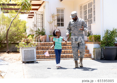 African American male soldier walking with his daughter holding a US flag African American male soldier walking with his daughter holding a US flag 65595005
