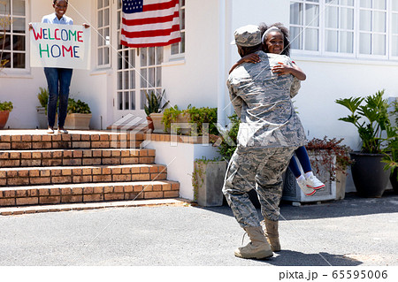 African American woman and her daughter standing welcoming an African American soldier 65595006