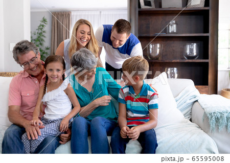Portrait of a three generation Caucasian family sitting on a couch at home 65595008