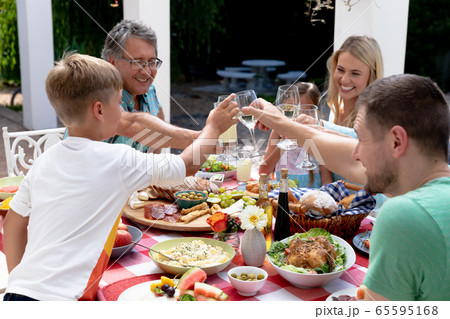 Caucasian family sitting at table during a family lunch in the garden Caucasian family sitting at table during a family lunch in the garden 65595168