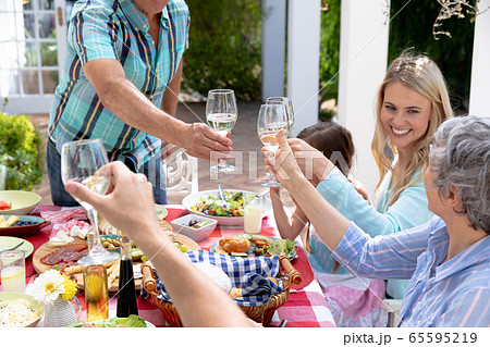 Caucasian family sitting at table during a family lunch in the garden 65595219