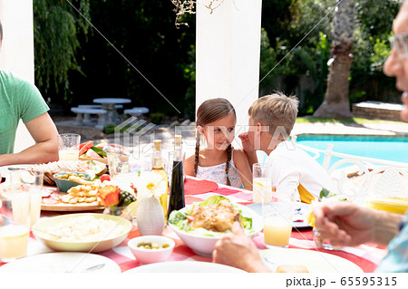Caucasian family sitting at table during a family lunch in the garden Caucasian family sitting at table during a family lunch in the garden 65595315