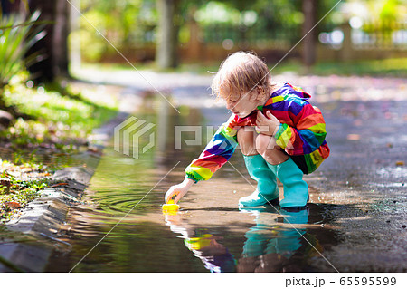 Kids in puddle in autumn rain. Waterproof wear Kids in puddle in autumn rain. Waterproof wear 65595599