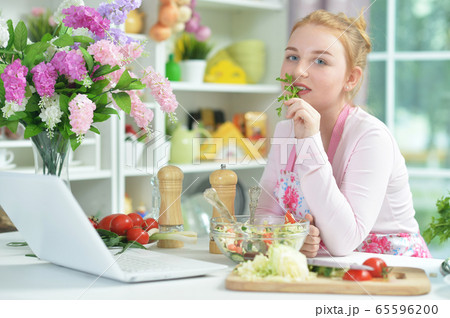 Cute teen girl preparing fresh salad on kitchen table 65596200