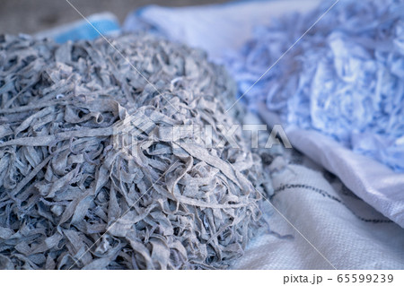 Fabric scraps, old clothing and textiles are cut into strips waiting for recycle. 65599239