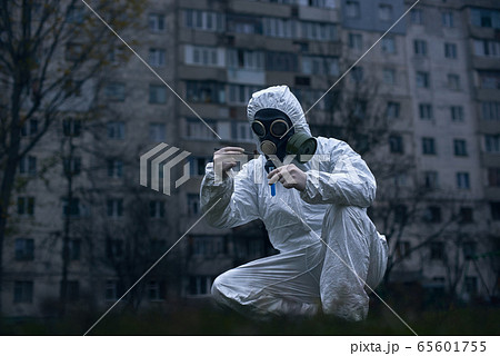 Scientist doing research outdoors, wearing white coverall and gas mask Scientist doing research outdoors, wearing white coverall and gas mask 65601755