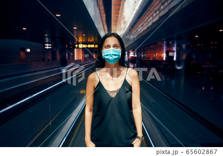 Woman in protection face mask posing in modern shopping mall or airport Woman in protection face mask posing in modern shopping mall or airport 65602867