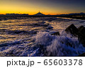 夕焼けでオレンジ色に染まる空と富士山と波しぶき 65603378