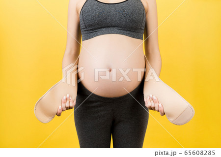 Close up of pregnant woman putting on a bandage at 65608285