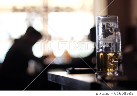 A drunk glass of light beer in a dark bar 65608935