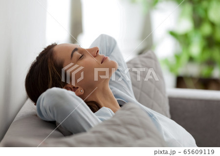 Happy satisfied mixed race female freelancer relaxing on comfortable sofa. Happy satisfied mixed race female freelancer relaxing on comfortable sofa. 65609119