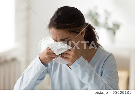 Unhappy millennial lady feeling unwell, wiping runny nose. Unhappy millennial lady feeling unwell, wiping runny nose. 65609139