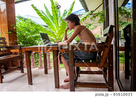 Coronavirus. Quarantine Online training education and freelance work. Computer, laptop and young white man working from home during. COVID-19 pandemic in the world. Side view. Stay at home. 65610035