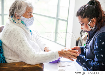 Senior woman getting a manicure at home during Covid-19 pandemic Senior woman getting a manicure at home during Covid-19 pandemic 65611410