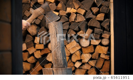 Chopping wood with an axe in woodpile - axe on the log 65611951