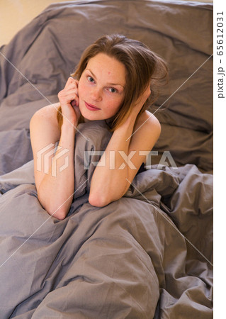 Young girl sitting in bed alone, hiding in blanket Young girl sitting in bed alone, hiding in blanket 65612031