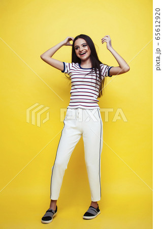 lifestyle people concept: pretty young school teenage girl having fun happy smiling on yellow background lifestyle people concept: pretty young school teenage girl having fun happy smiling on yellow background 65612920