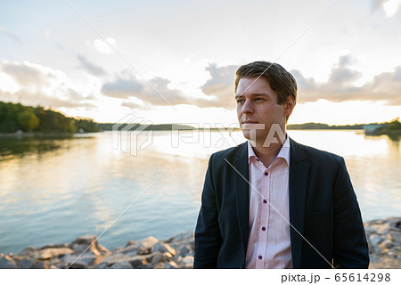 Young handsome businessman thinking in front of beautiful scenic shore 65614298