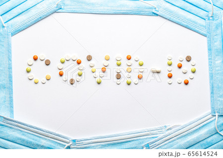 covid-19 inscription with pills and capsules and a blue disposable medical protective mask layout on a white background copy space. Coronavirus, medicine and health, safety concept. covid-19 inscription with pills and capsules and a blue disposable medical protective mask layout on a white background copy space. Coronavirus, medicine and health, safety concept. 65614524