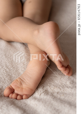 Childhood, sleep, relaxation, family, lifestyle concept - Feet of sleeping children lying randomly carelessly against a beige white plaid 65614763