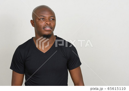 Happy young handsome bald African man thinking 65615110