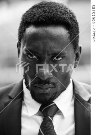 Face of stressed African businessman looking angry in black and white Face of stressed African businessman looking angry in black and white 65615285