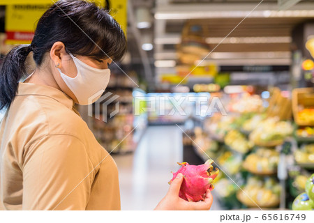 Overweight Asian woman with mask for protection from corona virus outbreak shopping inside 65616749