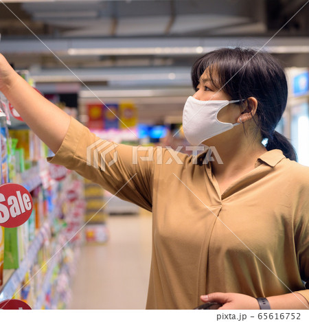 Overweight Asian woman with mask for protection from corona virus outbreak shopping inside Overweight Asian woman with mask for protection from corona virus outbreak shopping inside 65616752