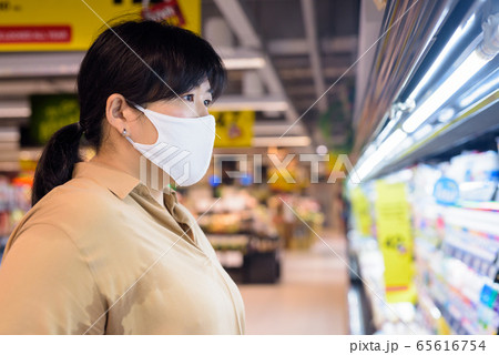 Profile view of overweight Asian woman with mask shopping inside supermarket Profile view of overweight Asian woman with mask shopping inside supermarket 65616754