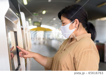 Overweight Asian woman with mask buying ticket for the sky train station Overweight Asian woman with mask buying ticket for the sky train station 65616763