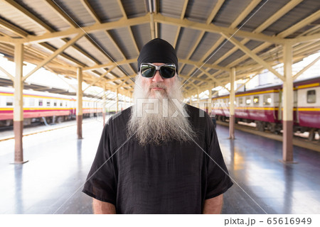 Portrait of mature bearded rebellious hipster man with sunglasses at the railway station 65616949
