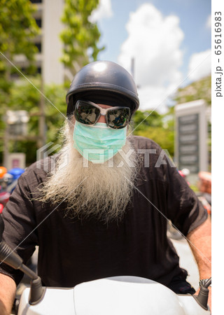 Face of mature bearded hipster man with sunglasses and mask riding motorcycle Face of mature bearded hipster man with sunglasses and mask riding motorcycle 65616983