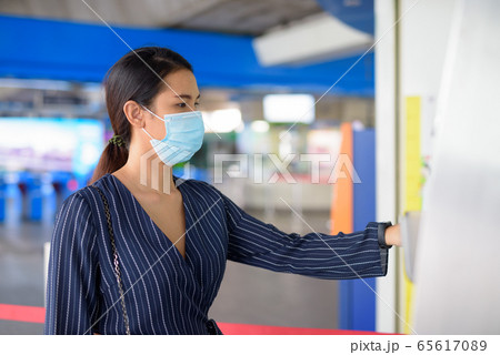 Young Asian businesswoman with mask buying ticket at the skytrain station 65617089