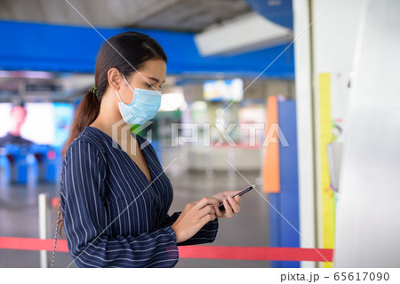 Young Asian businesswoman with mask buying ticket using phone at the skytrain station 65617090
