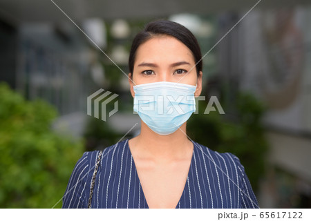 Face of young Asian businesswoman with mask for protection from corona virus outbreak in the city 65617122
