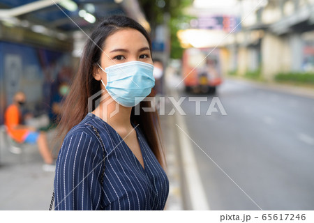 Young Asian businesswoman with mask for protection from corona virus outbreak waiting at the bus 65617246