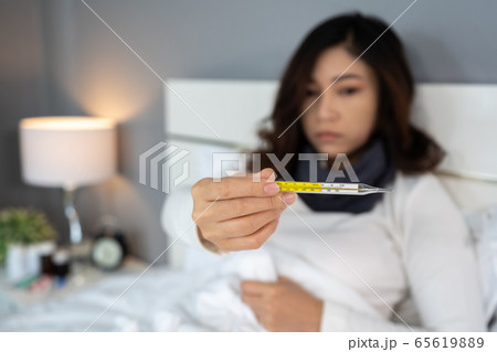 sick woman using thermometer and showing high 65619889