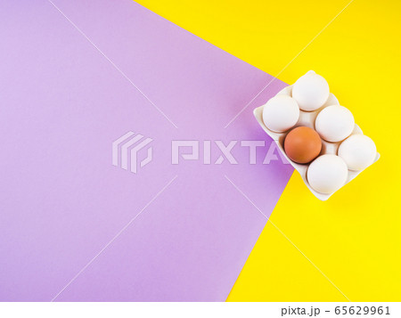 White and one brown egg on yellow and purple White and one brown egg on yellow and purple 65629961