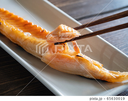 グリルで焼いた鮭のハラスを箸でほぐしているクローズアップ。 グリルで焼いた鮭のハラスを箸でほぐしているクローズアップ。 65630019
