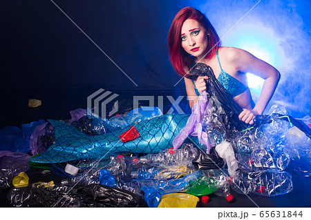 Fantasy mermaid in deep ocean shocked because water pollution. Plastic water bottles and bags pollution on sea floor. Environmental problem. 65631844