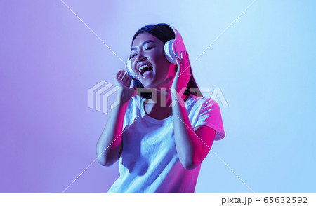 Wireless headphones and favorite music. Happy asian woman singing Wireless headphones and favorite music. Happy asian woman singing 65632592